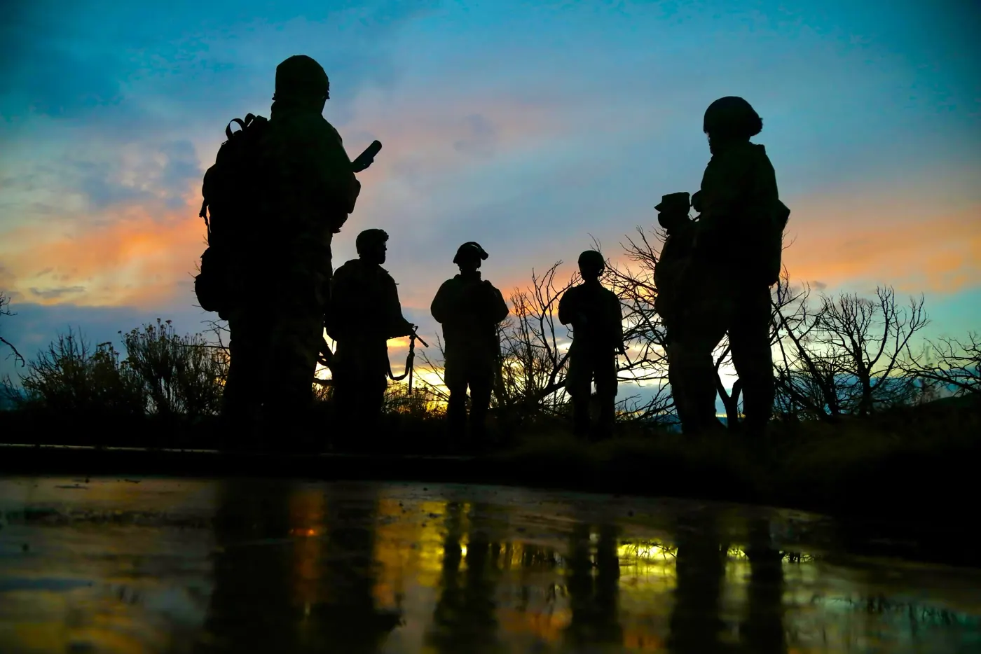Soldiers silhouetted against a sunset sky