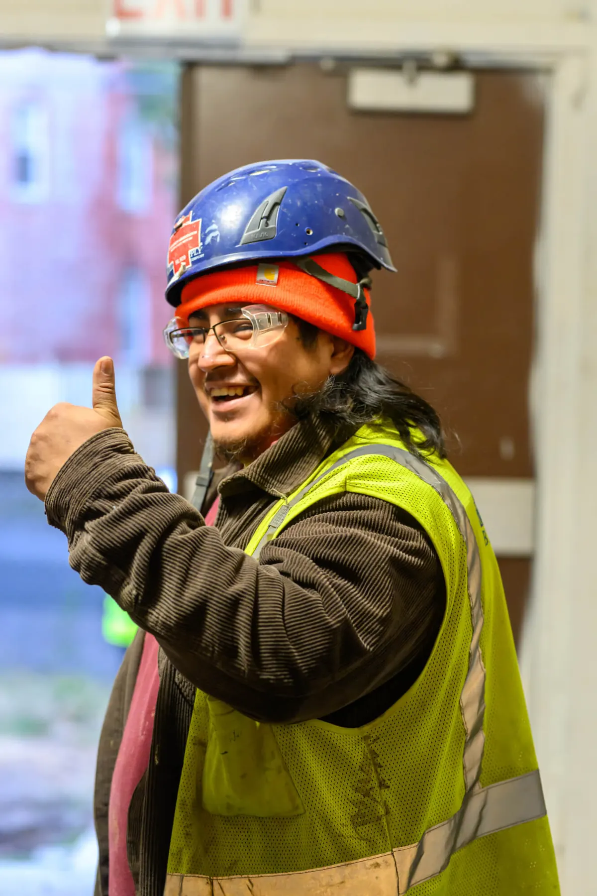 Smiling crew member in hard hat and hi-vis giving a thumbs-up